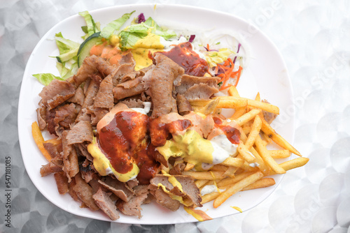 Doner kebab on a plate with French fries, salad and various sauces, popular fast food from Turkish cuisine, copy space, high angle view from above