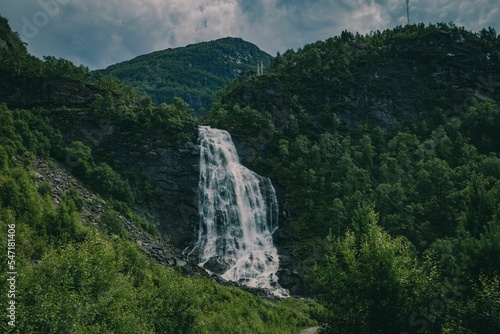 Long exposure shot of a waterfall in a valley emerging from the forest in Bergen area photo