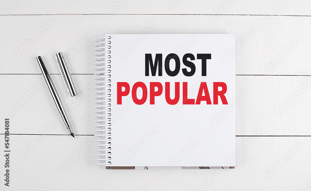 MOST POPULAR text written on notebook on the wooden background MOST POPULAR text written on notebook on the wooden background