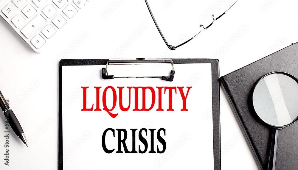 LIQUIDITY CRISIS text written on paper clipboard with office tools
