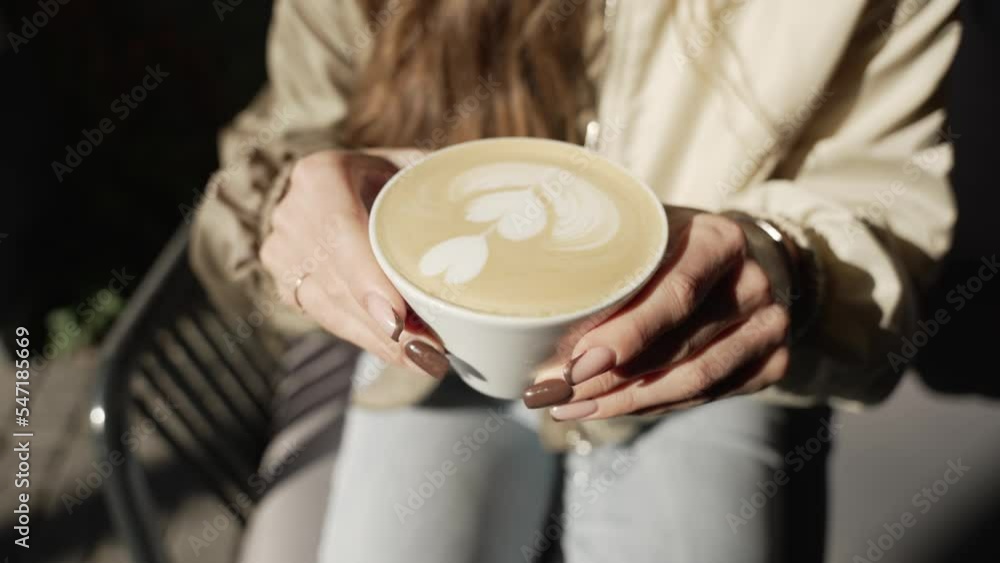 Cappuccino with milk, close-up. The girl takes a mug with coffee in her hands Cappuccino with milk, close-up. The girl takes a mug with coffee in her hands