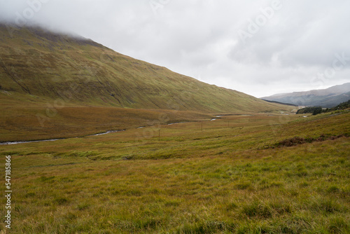 Hilly terrain with dry grass and cloudy sky photo