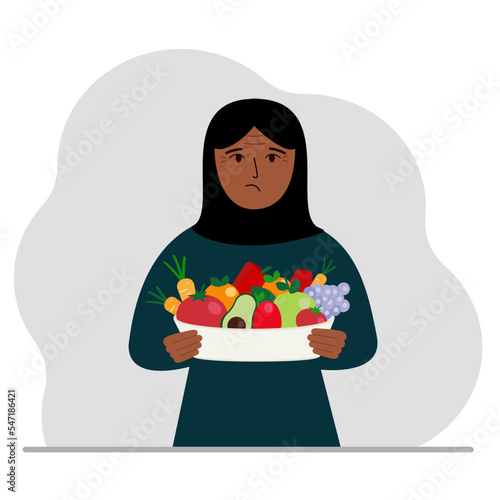 A muslim woman with a large plate of healthy organic food - vegetables and fruits. The concept of healthy food, healthy lifestyle, vegetarianism, agriculture.