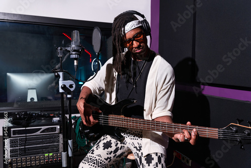 Black guitarist playing electric guitar and singing in studio photo