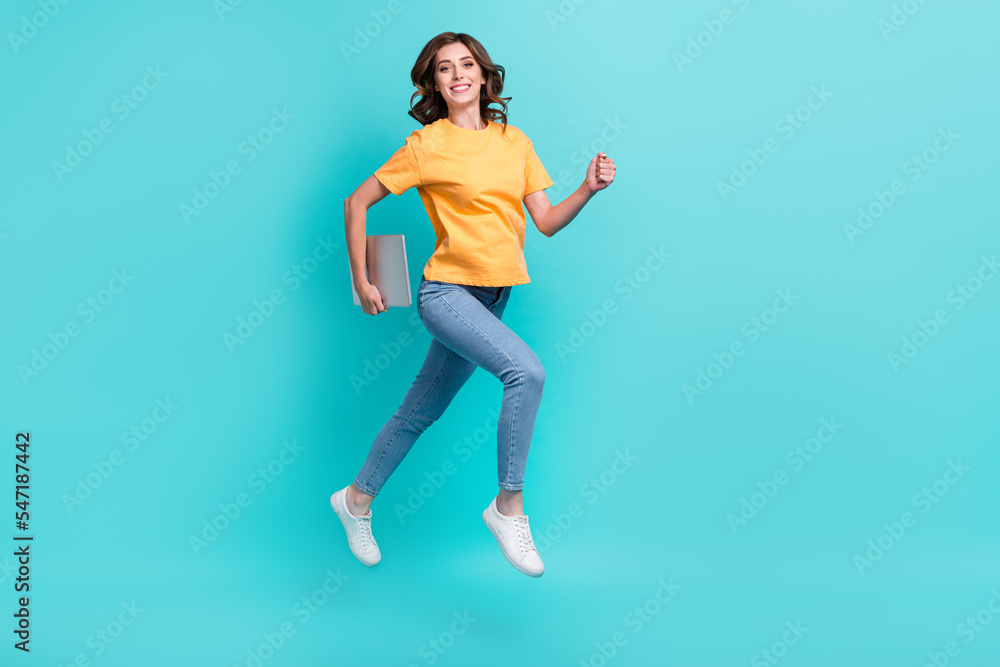 Full length photo of shiny adorable lady wear yellow t-shirt jumping high holding modern gadget isolated turquoise color background
