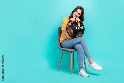 Full length photo of sweet dreamy lady wear yellow t-shirt driving car looking empty space sitting chair isolated turquoise color background