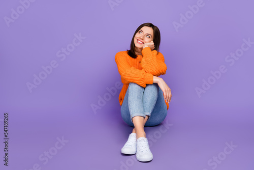 Full body photo of stunning young girl sit look dreamy empty space dressed stylish orange knitted look isolated on purple color background © deagreez
