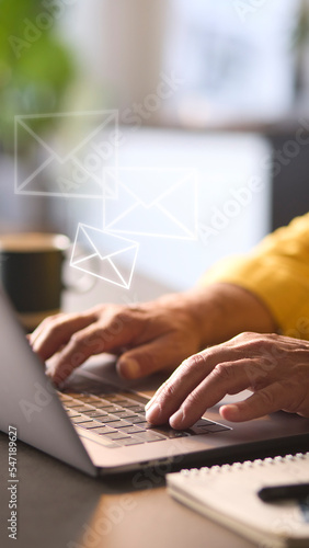 Email Concept With Man Using Laptop With Graphic Overlay Of Envelopes