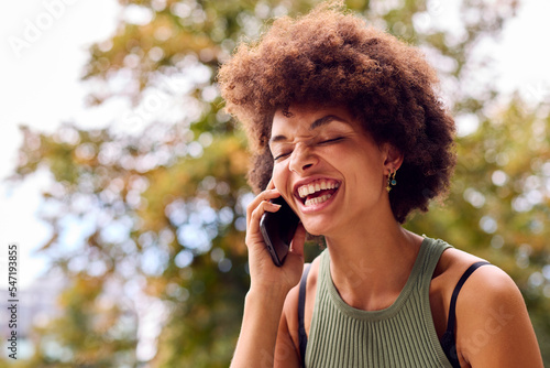 Smiling Young Woman Outdoors Laughing As She Talks On Mobile Phone
