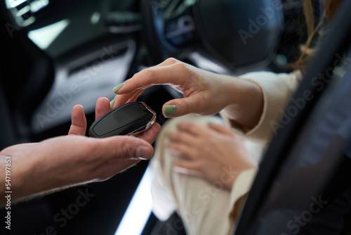 Well-groomed female hand taking auto key fob from salesperson