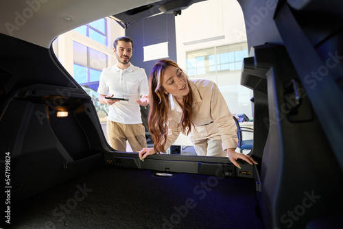 Pleased young female buyer inspecting automobile interior