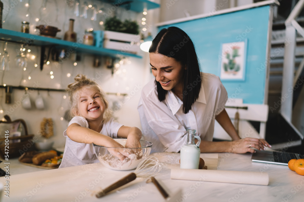 Cheerful mother and daughter preparing dough in kitchen Cheerful mother and daughter preparing dough in kitchen