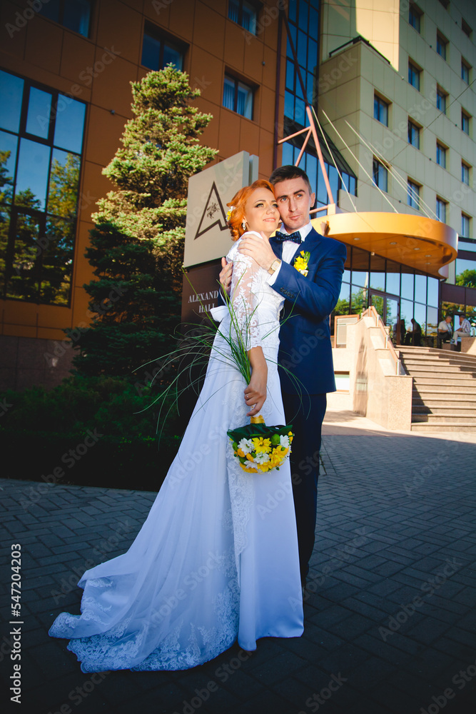 Young beautiful couple in a blue suit and white wedding dress with a bouquet
