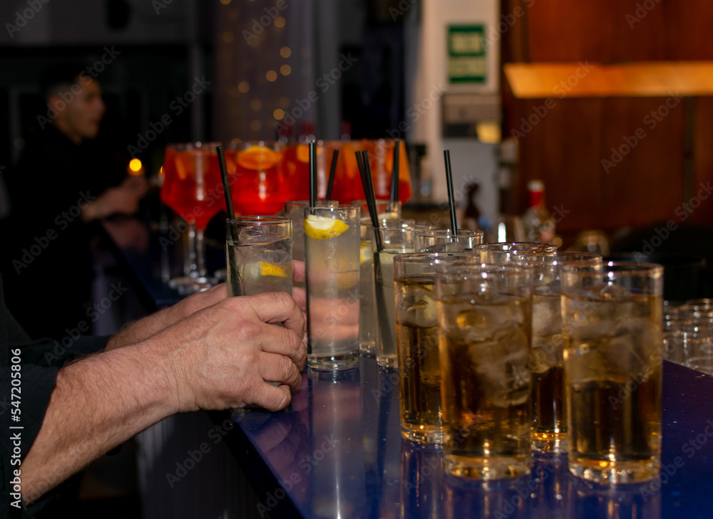 Barman sirviendo vasos y copas de cocktail en barra de bar.