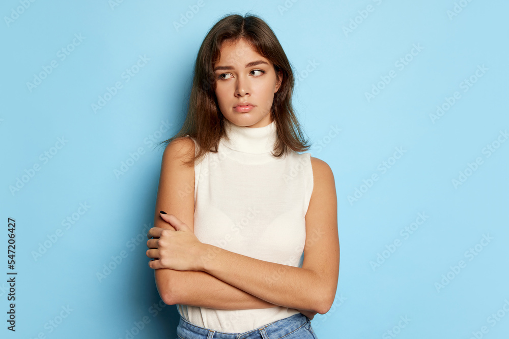 Portrait of young beautiful woman posing with sad expression isolated over blue studio background. Feeling disappointed Portrait of young beautiful woman posing with sad expression isolated over blue studio background. Feeling disappointed