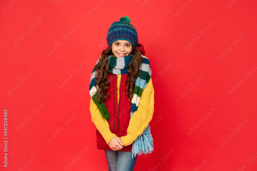 cheerful kid in knitted winter hat and scarf on red background, cold winter cheerful kid in knitted winter hat and scarf on red background, cold winter
