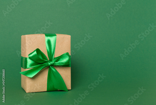 Gift box with green ribbon bow on color background