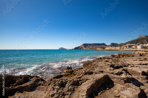 Panorámica de la zona rocosa de Calpe con las olas  del mar Mediterráneo rompiendo en sus piedras bajo un precioso cielo azul soleado en un día de otoño. © Beatriz