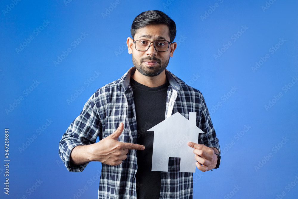 Man showing house loan concept, isolated on blue background. Man showing house loan concept, isolated on blue background.