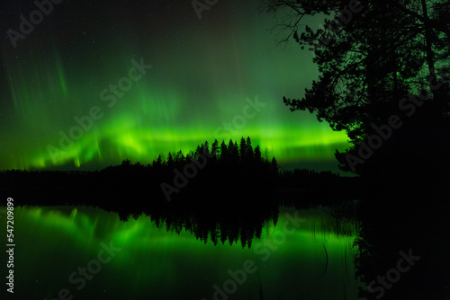 Strong Aurora borealias by the lake in eastern Finland in autumn night.