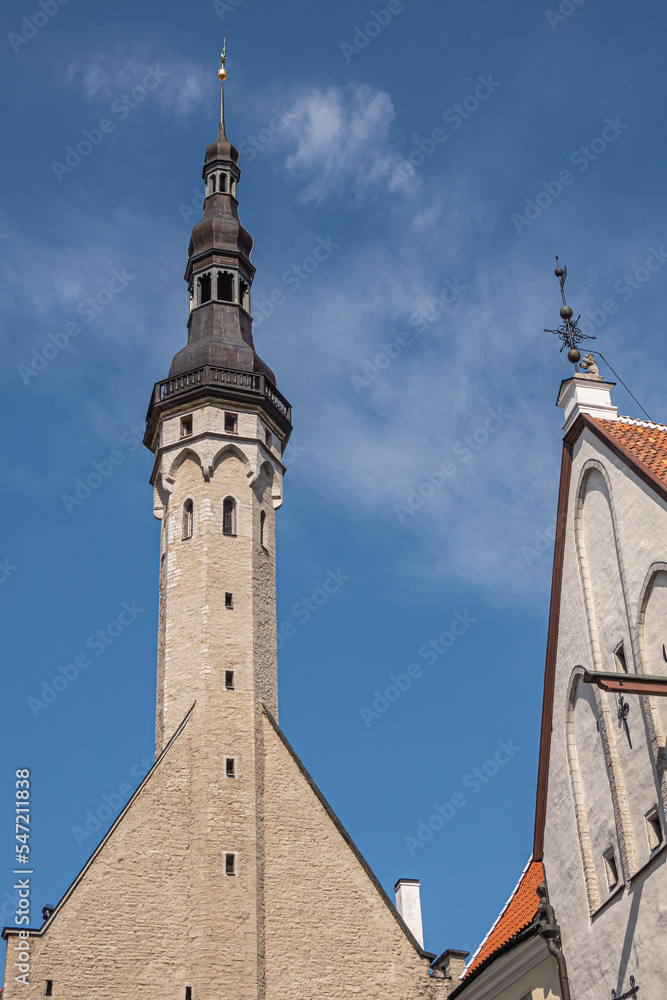 Estonia, Tallinn - July 21, 2022: Closeup, Town Hall tower against blue sky seen from Raekoja street. Facades on sides