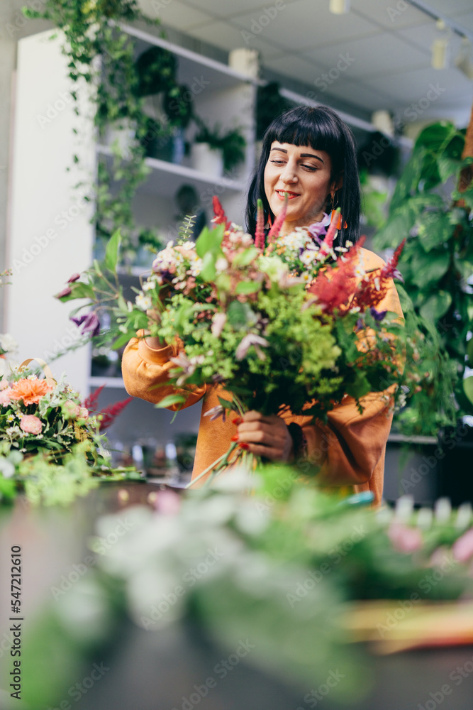 Woman arranges bouquet from flowers in florist shop