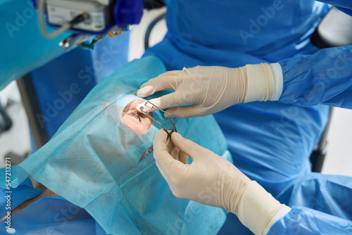 Doctor holding eyelid expander during the surgery