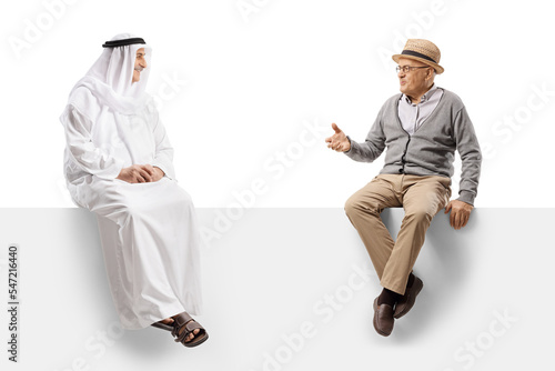 Senior gentleman sitting on a panel and talking to a muslim man in ethnic clothes