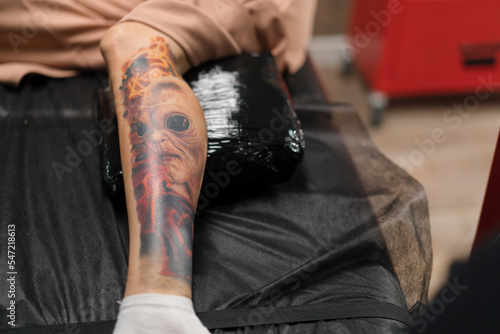 Tattoo with an alien on the leg of a woman during a tattoo correction session in a tattoo studio