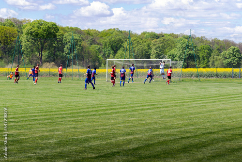 Young men play soccer and the goalkeeper catches the ball.