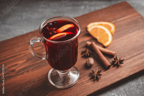 Mulled red wine in a glass and spices on wooden background