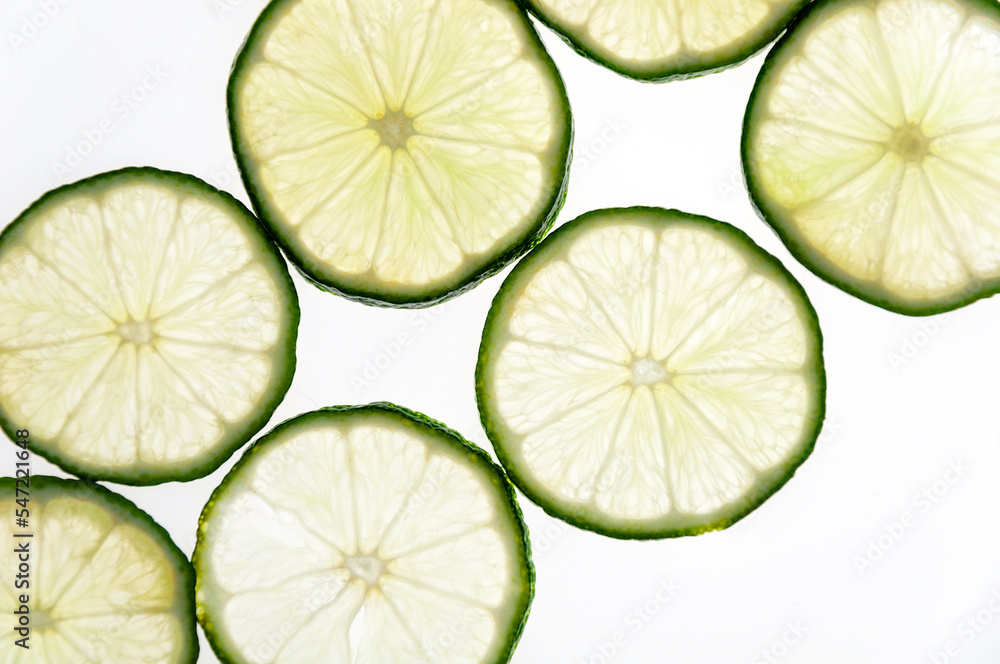 Slices of green fresh lime on a white background on the lumen. Close-up shooting. Slices of green fresh lime on a white background on the lumen. Close-up shooting.