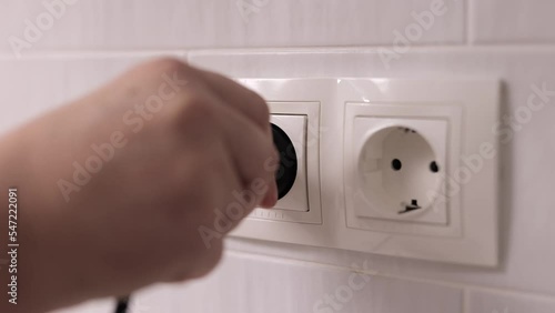 Woman hands switch on the power plug into the white electrical socket. Main pulls out the electrical plug in socket wire.