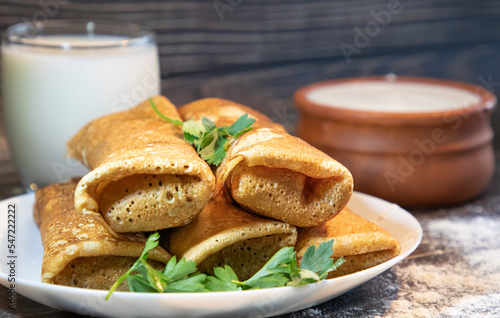 Homemade savory pancakes stuffed with meat on the background of milk and cream 