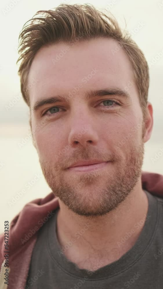 VERTICAL VIDEO: Close up, young man standing on the beach VERTICAL VIDEO: Close up, young man standing on the beach