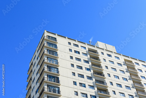 Exterior view of a typical multifamily mid and high rise residential building under blue sky. Looking up at rental apartment, college dorm, condominium, assisted-living facility building