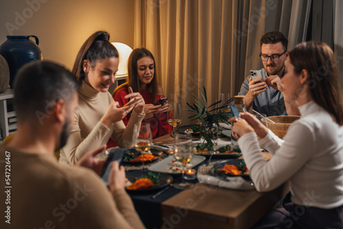Five people look at their phones at dinner