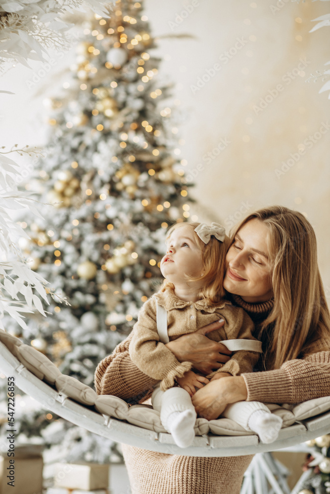 Mother with her daughter by the christmas tree at home Mother with her daughter by the christmas tree at home