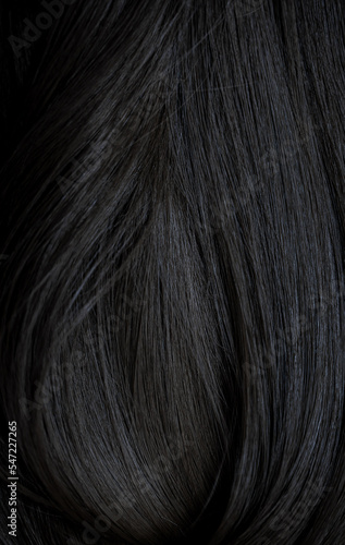 Brunette or black hair. Female long dark hair in black. Beautifully laid curls. Closeup texture in a dark key. Hairdressing  hair care and coloring. Shading gray hair. Background with copy space.
