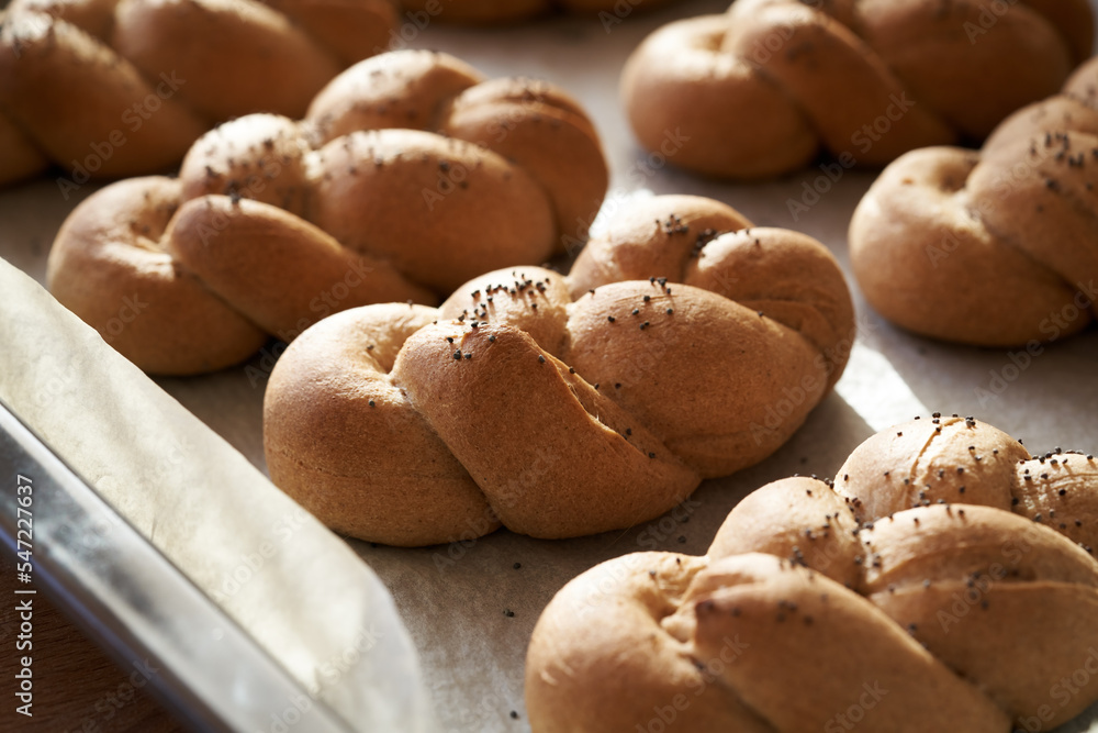 Homemade braided bread rolls made from whole grain spelt flour, sprinkled with poppy seeds