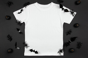 White womens cotton t-shirt halloween mockup with pumpkins, spiders and bats on black background. Design t shirt template, print presentation mock up. Top view flat lay.
