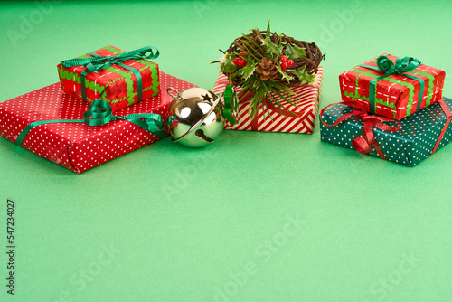 wrapped gifts, twig wreath and silver bell on green 