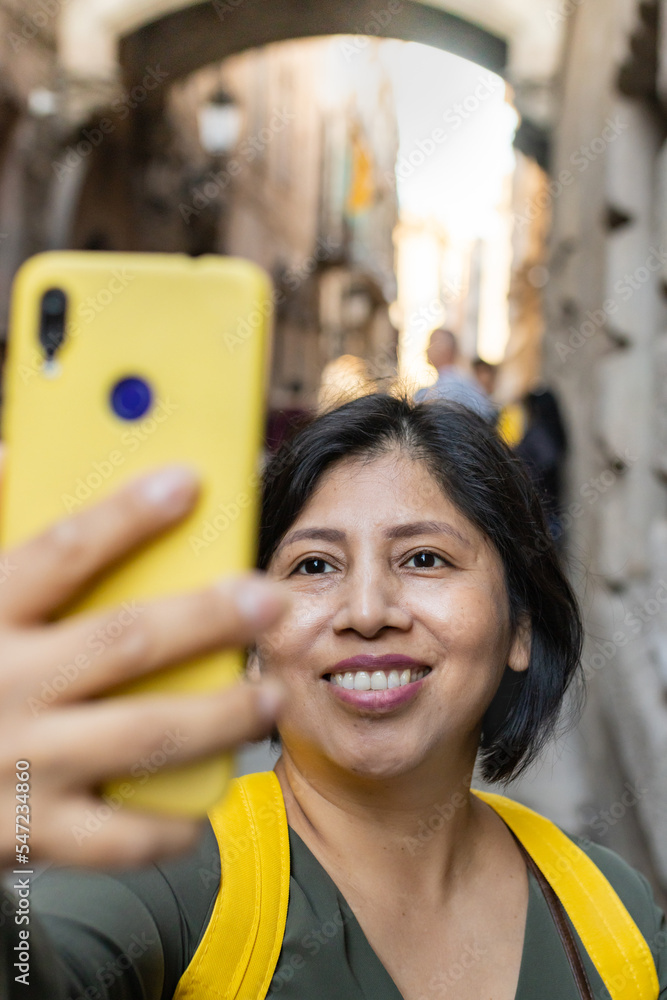 Happy Latina woman taking a selfie in the Gothic quarter of Barcelona ...
