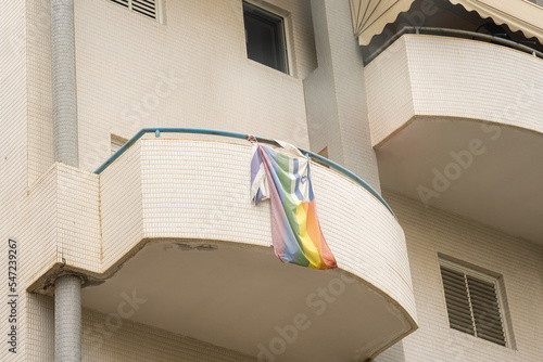 An old and faded gay flag hangs over an old and faded Israeli flag on a balcony in Tel Aviv photo