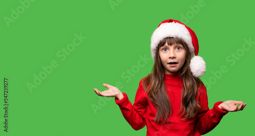 Merry Christmas and New Year. Very emotional surprised girls in a red Santa hat waiting for Christmas gifts. The child is overjoyed. Promotions, discounts, gifts