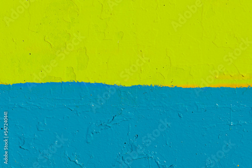 The flag of Ukraine on the fence. The surface of the concrete fence is painted yellow and blue. Texture surface for text. © Pokoman