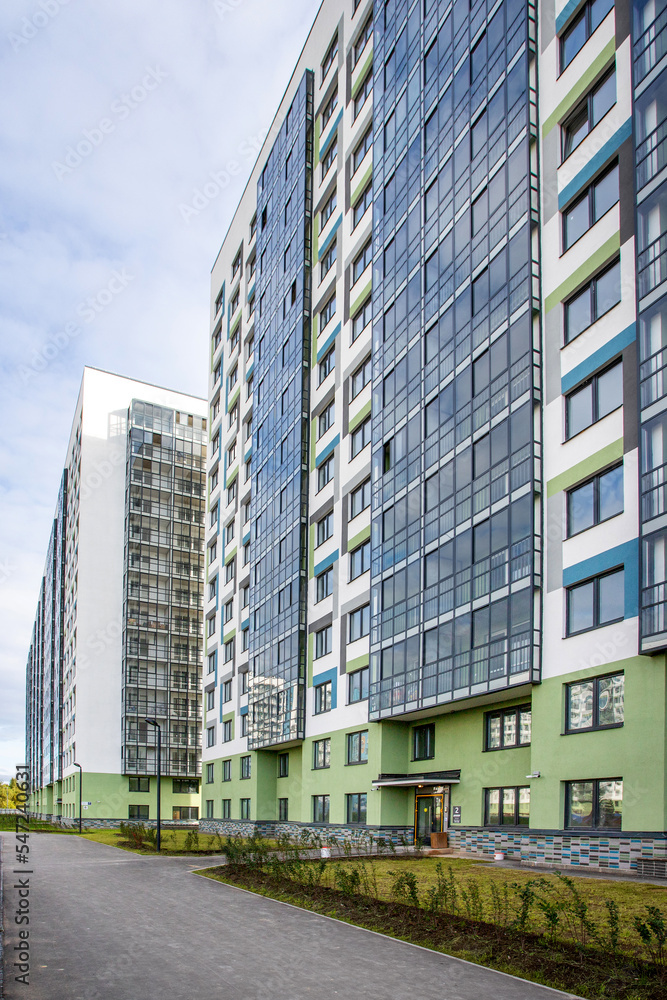 facade of a new building of white blue and green color with glass windows and balconies