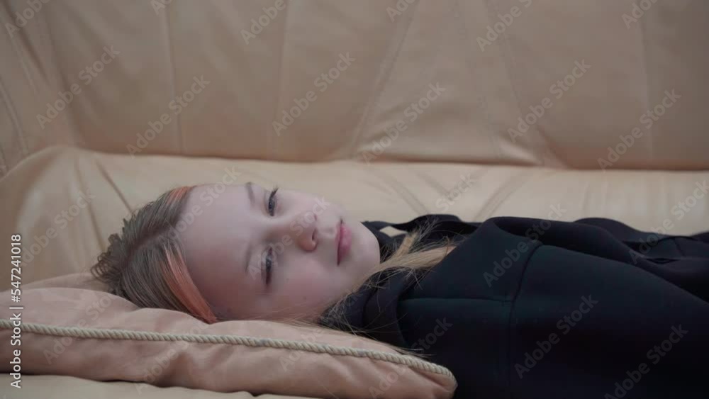Tired young girl lies on the sofa and gradually closes her eyes, she falls asleep. Tired young girl lies on the sofa and gradually closes her eyes, she falls asleep.