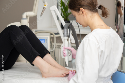 The doctor makes the procedure for the treatment of foot fungus. A patient receiving laser therapy for a toenail. Fungal infection on the nails. Treatment of onychomycosis with a medical laser.