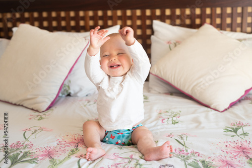 A happy baby girl learning how to sit by herself. She is wearing a modern, reusable cloth diaper